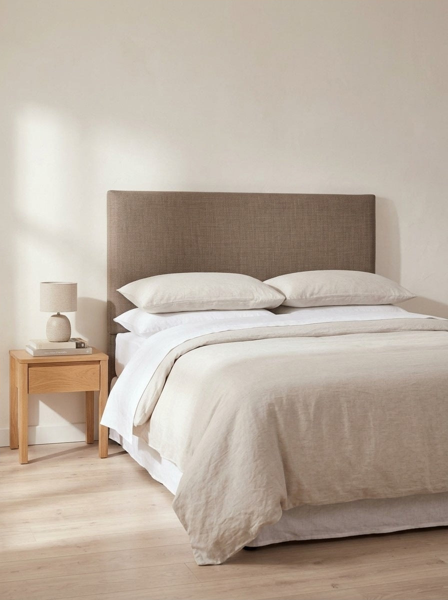 Repton headboard in Linoso Sand fabric on a made-up bed