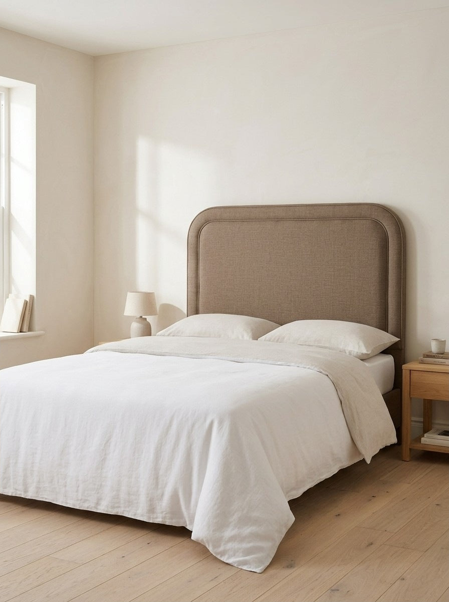 Amber headboard in Linoso Sand fabric on a made-up bed